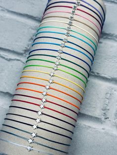 a stack of bracelets on top of a white brick wall next to a star necklace