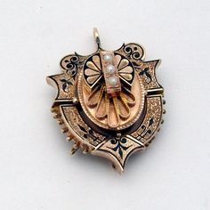 "Victorian era ornate 14 K (.585) rose gold locket pendant, decorated with Seed Pearls and black enamel. It was a combination of brooch and pendant, but the pin was removed (in current condition it is a pendant). This magnificent antique locket is 1 1/2\" long, 1 1/8\" wide and weighs 12.3 grams. The pendant is slightly bent, and there is some enamel loss  due to age. EA2188" Ornate Engraved Brooch, Victorian Locket Pendant Brooches, Victorian Brooches With Locket Pendant, Gold Locket-shaped Brooch, Ornate Gold Locket Brooches, Victorian Black Enamel Pendant Jewelry, Antique Enamel Locket Jewelry, Gold Pendant Locket Brooch, Gold Pendant Locket Brooches