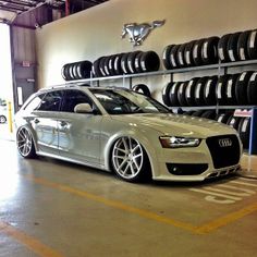 a white car is parked in front of some tires