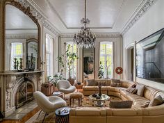 a living room filled with lots of furniture and a chandelier hanging from the ceiling