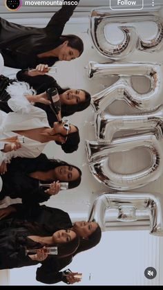 four women standing in front of giant balloons that spell out the word 50 on it