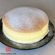 a cake with powdered sugar on top sits on a black plate