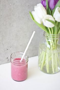 a glass jar filled with pink and white flowers next to a mason jar full of purple and white tulips