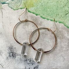 These clear quartz double pointed crystal hoop earrings are truly one-of-a-kind! These earrings are handcrafted out of 18kt gold over sterling silver. As these are made with natural stone, each piece is unique. Variations in tone and color are normal and add to the beauty of these one-of-a-kind earrings. By Jax Kelly. Dimensions: Earrings: 2.75"L x 1.5"W Stone: .8" x .2"W Handmade Clear Hoop Jewelry, Minimal Earrings, Crystal Hoop Earrings, Earring Sale, Clear Quartz Crystal, Gold Hoops, Gold Hoop, Gold Hoop Earrings, Clear Quartz