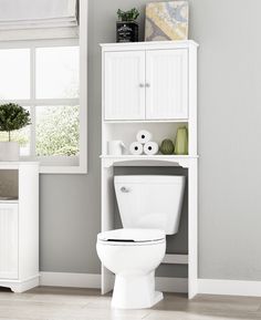 a white toilet sitting in a bathroom next to a cabinet with towels on top of it