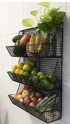 three tiered metal fruit and vegetable rack in the corner of a white tiled wall