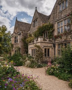 an old house with lots of flowers growing around it