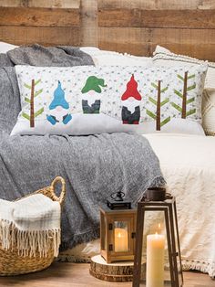 a bed with pillows and blankets on top of it next to a basket filled with candles