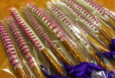 there are many candy sticks wrapped in cellophane and purple ribbon on the table