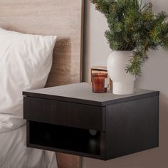 a white vase sitting on top of a nightstand next to a bed