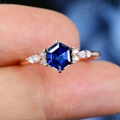 a woman's hand holding an engagement ring with a blue sapphire and diamond accents