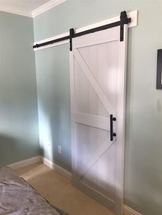 an open sliding barn door in a bedroom with light blue walls and carpeted flooring