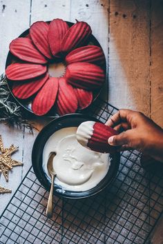 a person is decorating some red flowers with white icing and star decorations on the table