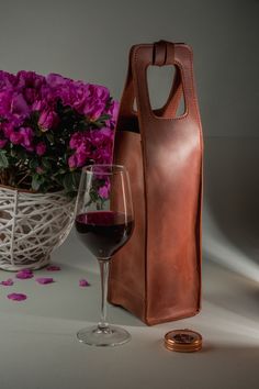 a glass of wine next to a leather bag