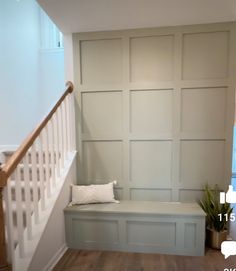 an empty room with a bench and stairs in front of the wall, next to a potted plant