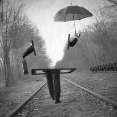 a person holding an umbrella over their head on train tracks