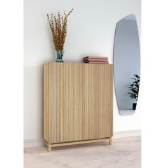 a wooden cabinet sitting next to a mirror and vase with flowers on top of it