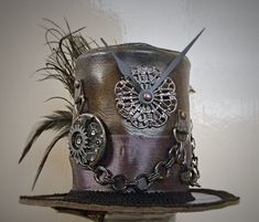 IMPORTANT NEWS!!  Due to the UK leaving the EU, postage prices have increased but have kept them as low as I can for my customers. If you would like to purchase more than one item, please contact me first so I can invoice you with the lowest postage price. Unique, leather mini top hat. Steampunk style. Attaches to the head by 2 alligator clips Approx Size: Brim Width 15.5cm                         Height 10cm Bespoke mini top hats available. One of a kind Details: Leather top hat Metal details Metal buckle Ribbon band Clock parts Metal chain Black feathers Peacock feather Metal spike Tracked and signed postage worldwide available, please contact me before purchasing. Steampunk High Crown Top Hat For Cosplay, Steampunk Costume Top Hat, Steampunk Top Hat With High Crown For Themed Events, Steampunk Mini Hats For Halloween, Vintage Top Hat With High Crown For Cosplay, Vintage High Crown Top Hat For Cosplay, Steampunk Brimmed Mini Hats For Cosplay, Steampunk High Crown Costume Hat, Steampunk High Crown Mini Hat For Themed Events