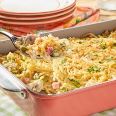 a pink casserole dish filled with rice and vegetables on a checkered table cloth