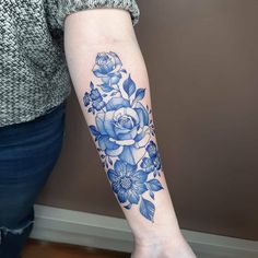 a woman's arm with blue flowers and leaves on the left side of her arm