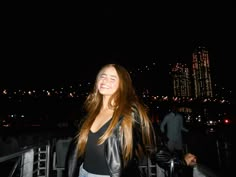 a woman standing on top of a bridge at night