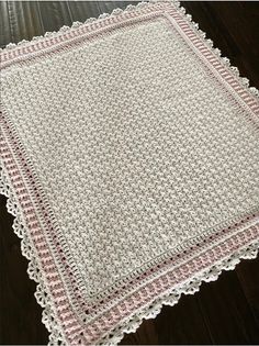 a white crocheted tablecloth with pink trimmings on a wooden floor