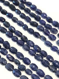 several strands of blue sapphire beads on a white surface, with one strand in the middle