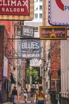 people are walking down the street under neon signs