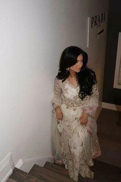 a woman in a white dress is standing on some stairs