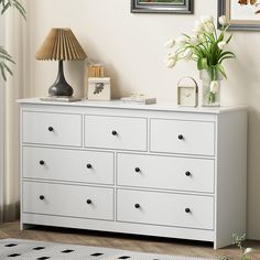 a white dresser with flowers and pictures on it