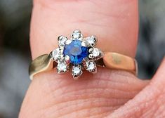 a close up of a person's hand holding a ring with a blue stone