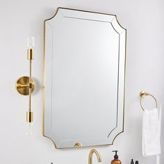 a bathroom with a sink, mirror and gold faucet on the wall above it