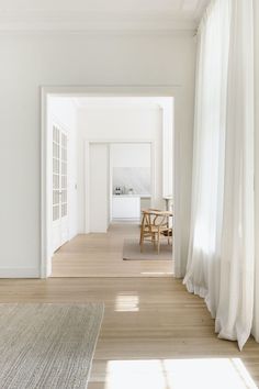 an empty room with white walls and wooden floors, along with a table in the middle