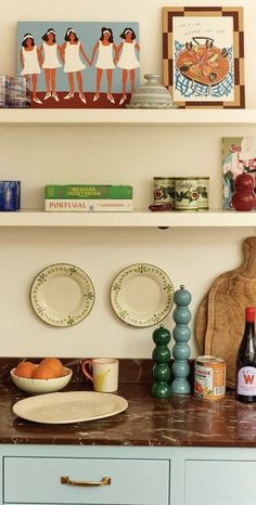 a kitchen counter with plates and bowls on it next to two shelves filled with books