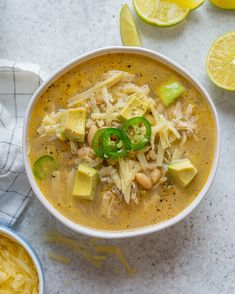 a white bowl filled with soup next to sliced lemons and lime slices on the side