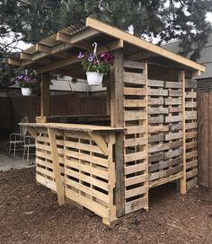 an outdoor bar made out of pallets and wooden planks with potted plants on top