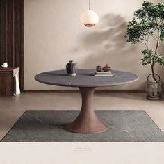 a round table with two vases on it and a plant in the corner next to it