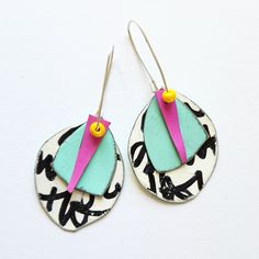 a pair of earrings with colorful designs on them sitting on top of a white surface