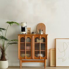 a wooden cabinet sitting next to a potted plant