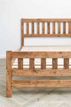 a wooden bed frame sitting on top of a hard wood floor next to a white wall