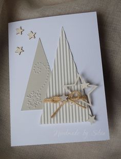 a white card with a christmas tree and star decoration on it's side, sitting on a tan fabric background