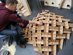 a man sitting on a chair next to a pile of wooden blocks in a room