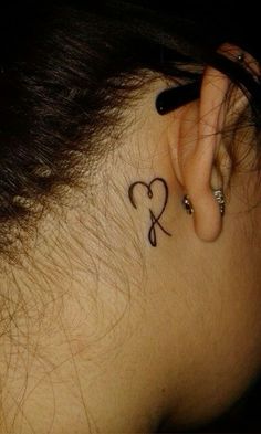 a woman with a heart tattoo behind her ear