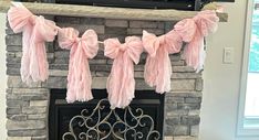 a fireplace decorated with pink bows and streamers for a party or bridal event