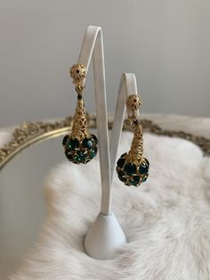 These are vintage mid-century clip on earrings. They are in a gold tone metal that is bright and shows no signs of wear or tarnish. The base of the earrings have round shape emerald tone rhinestones that form a sphere. The earrings are in excellent condition.Measurements:Length: 2" | Width: .75"Unless otherwise stated all vintage items are used and may have minor to moderate wear or discoloration considering the age of the item. Most items have been hand washed, spot cleaned, or professionally d Vintage Metal Earrings For Formal Occasions, Retro Dangle Jewelry For Formal Occasions, Antique Gold Party Earrings, Antique Gold Earrings For Party, Vintage Chandelier Dangle Earrings For Anniversary, Vintage Gold Bridal Earrings, Vintage Metal Earrings For Evening, Retro Dangle Earrings For Formal Occasions, Vintage Dangle Earrings For Formal Occasions