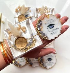 a person holding some small boxes with gold and white decorations on them