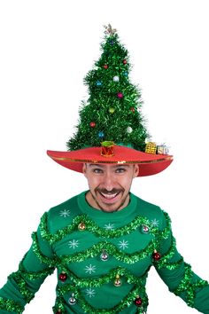 a man wearing a green christmas sweater with a red hat on top of his head