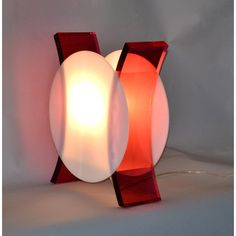 a red and white lamp sitting on top of a table next to a light bulb