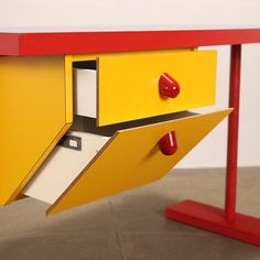 a yellow and red desk with two drawers on each side that is open to reveal a file cabinet