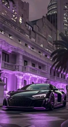 a black sports car parked in front of a tall building with purple lights on it